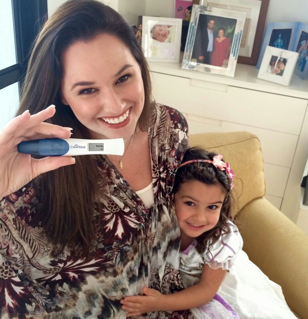 Mariana Belém, ao lado de sua pequena Laura, mostra o resultado positivo do teste de gravidez. (Foto: Arquivo Pessoal / Divulgação)