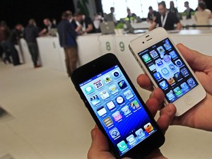 Usuário compara a nova versão do smartphone (à esquerda) com o iPhone 4S durante o lançamento do aparelho em Bruxelas. O novo iPhone está mais comprido, leve e fino. (Foto: Yves Herman/Reuters)