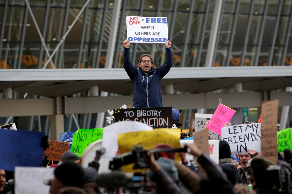 Homem protesta em terminal do aeroporto John F. Kennedy, em Nova York (Foto: Andrew Kelly/Reuters)