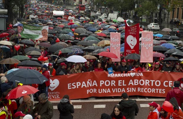 Multidão marcha sob chuva em Madri levando faixas e cartazes contrários à lei que permite o aborto na Espanha, promulgada em 2010 (Foto: Pierre-Philippe Marcou/AFP)