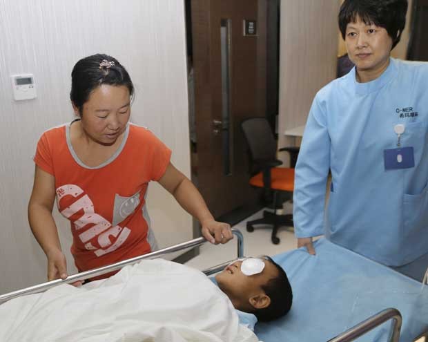 Guo Bin, 6, está acompanhado por sua mãe Wang Wenli antes de realizar uma cirurgia de implante na cidade chinesa de Shenzhen (Foto: C-MER (Shenzhen) Dennis Lam Eye Hospital/ Reuters)