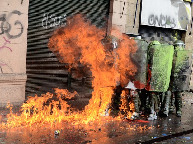 Estudantes atacam policiais com bombas e tinta durante protesto em santiago no Chile. Milhares de estudantes foram às ruas nesta quinta-feira (11) para protestar por educação gratuita no país. (Foto: Pablo Tapia/AFP)