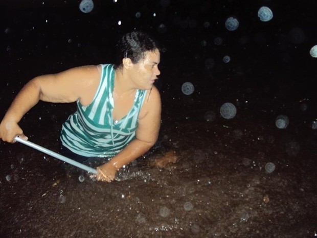 Moradora tenta tirar água de dentro de casa (Foto: Douglas Cossi / Ilha de Notícias)