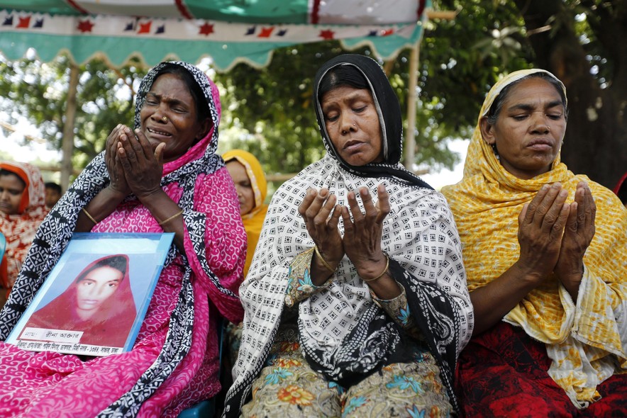 Mulheres rezam no local onde , há um ano, caiu o edifício Rana Plaza, um prédio que funcionava como confecção de roupas, em Dacca, Bangladesh. Mais de mil pessoas morreram na tragédia