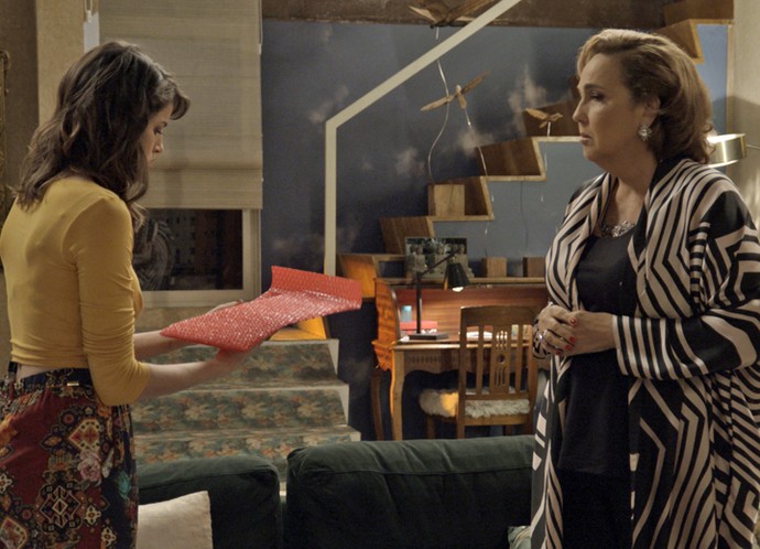  Lucrécia observa Camila ver o que tem no pacote misterioso (Foto: TV Globo)