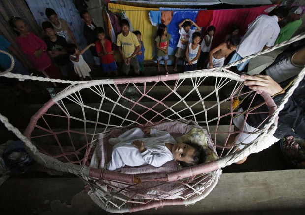 Bebê descansa em rede improvisada em cesta de basquete em ginásio usado como abrigo para vítimas de enchente em Jabonga, no sul das Filipinas (Foto: Erik de Castro/Reuters)
