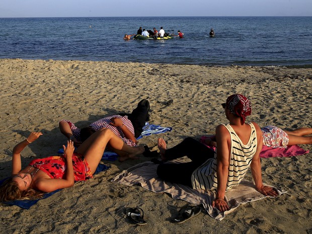 Turistas na ilha grega de Kos observam a chegada de imigrantes em bote, vindos da Turquia (Foto: Yannis Behrakis/Reuters)