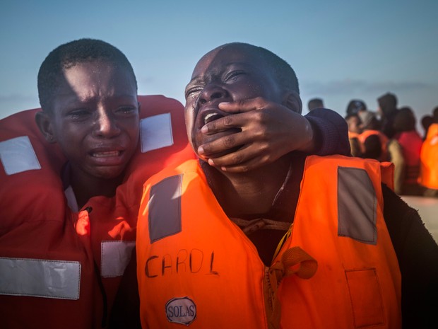 Irmãos choram durante operação de resgate no Mediterrâneo na quinta-feira (28). A mãe deles morreu na Líbia (Foto: Santi Palacios/AP)