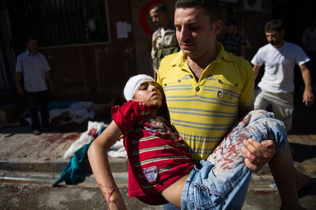 Homem carrega menino ferido em ataque das forças do regime sírio em Aleppo, na sexta-feira (10) (Foto: Phill Moore / AFP)