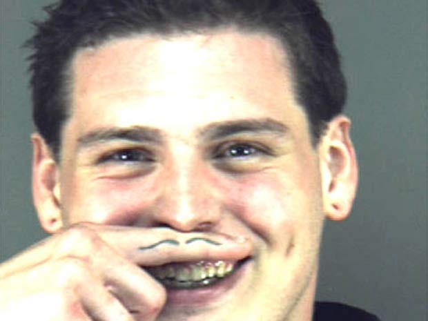 Ao posar para a foto depois de ser preso na Flórida (EUA) em 2010, um jovem fez gracinha e usou uma tatuagem em um dos dedos para criar um ‘bigodinho’ inusitado (Foto: Divulgação)