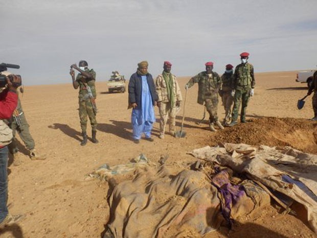 Voluntários e militares observam os corpos retirados da areia do Saara, ao norte de Arlit, no Níger (Foto: Almoustapha Alhacen/AP)