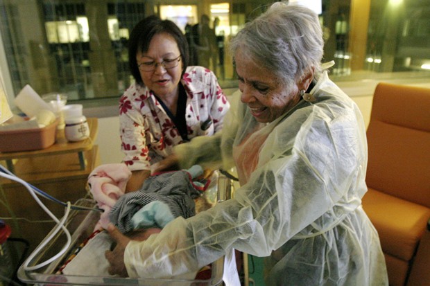   Voluntária Gertie Rogers, de 84 anos, coloca um recém-nascido em uma cama na UTI neonatal no Hospital Infantil da Universidade de Chicago  (Foto: AP Photo/Martha Irvine)