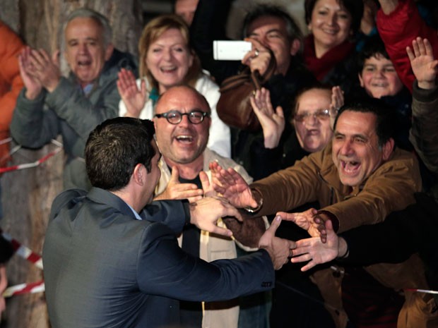 Alexis Tsipras, líder do partido Syriza, cumprimenta seus apoiadores do lado de fora da sede do partido em Atenas, neste domingo (25) (Foto:  AP Photo/Lefteris Pitarakis)