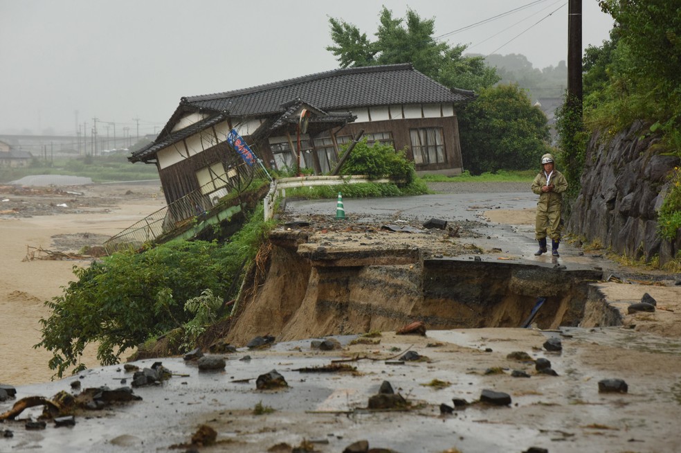 Um homem observa uma estrada destruída e uma casa danificada após uma forte inundação em Asakura, no Japão. Pelo menos 6 pessoas morreram e centenas foram afetadas com as enchentes que envolvem partes do sul do Japão  (Foto: Kazuhiro Nogi/AFP)