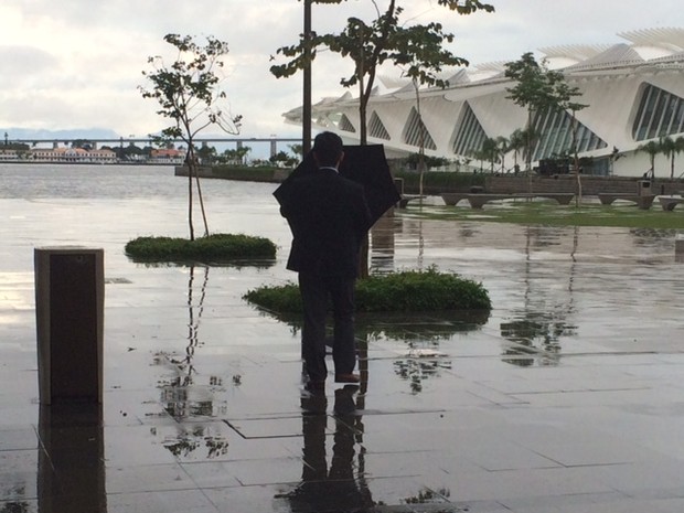 Homem abre guarda-chuvas na Praça Mauá, Centro do Rio (Foto: Alba Valéria Mendonça/G1)