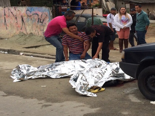 Iratã Martins da Costa chora ao lado do corpo do filho, Mateus Justino Costa, de 17 anos, morto na chacina de quarta-feira (8)  no Jardim Universo, em Mogi (Foto: Luis Corvini/ TV Diário)