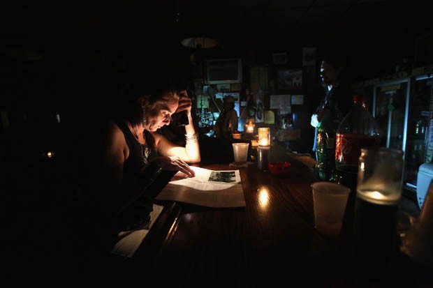 Desier Galjour lê jornal com ajuda de uma lanterna no Bar do BJ no bairro Bywater de Nova Orleans (Foto: John Moore/Getty Images/AFP)