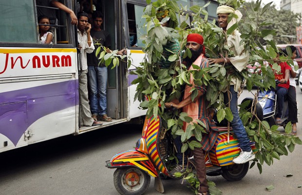 Ativistas enrolam-se com ramos de árvore em uma scooter e são observador por passageiros de ônibus. É um manifesto no Dia do Meio Ambiente, comemorado nesta terça-feira (5), para que as pessoas cuidem das árvores. A data é celebrada pela Organização das Nações Unidas para estimular a consciência global sobre questões ambientais. (Foto: AP)