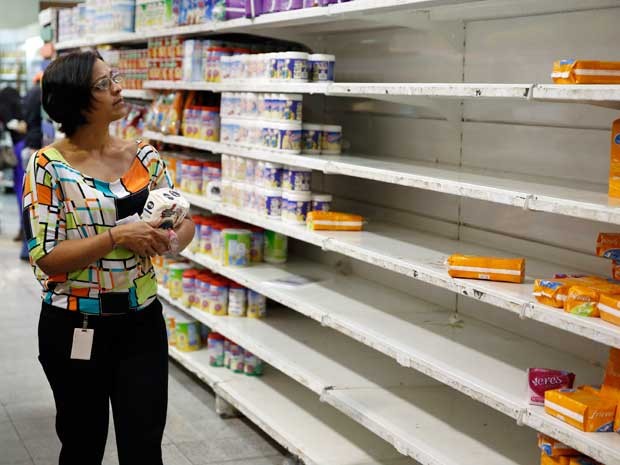 Mulher observa prateleiras quase vazias de supermercado na Venezuela. (Foto: Carlos Garcia Rawlins / Reuters)