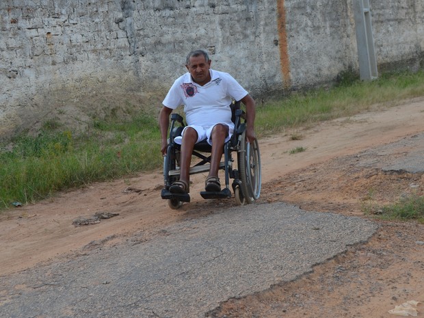 Ao sair de casa, aposentado enfrenta os buracos na rua sem asfalto. (Foto: Valéria Oliveira/ G1)