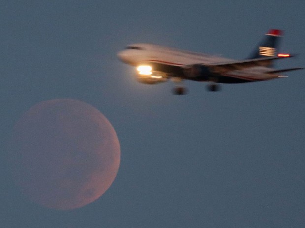 Avião comercial passa em frente à 'lua de sangue' durante eclipse lunar visto das proximidades do Aeroporto Nacional Reagan em Washington, nos EUA (Foto: Mark Wilson/Getty Images/AFP)