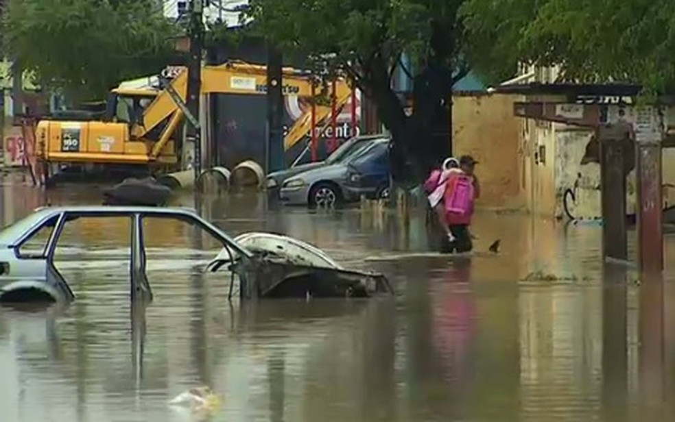 Pai carrega crian&ccedil;a nas costas para evitar o contato dela com a &aacute;gua suja. (Foto: Reprodu&ccedil;&atilde;o/TV Sergipe)