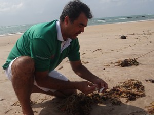 Elcio Oliveira recolhe lixo que encontra na areia da praia (Foto: Lucas Leite/G1)