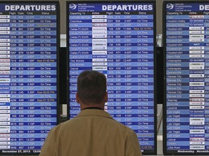 Homem olha para painel com informação sobre voos em aeroporto (Foto: Brennan Linsley/AP)