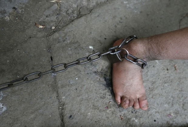 He Zili, de 11 anos, tem um de seus pés acorrentados. Ele vive na China e fica preso por atacar as pessoas, segundo seus familiares (Foto: William Hong/Reuters)
