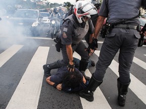 Policiais seguram manifestante no chão na rodovia Raposo Tavares, em São Paulo. Funcionários e estudantes da Universidade de São Paulo (USP) montaram barricadas bloqueando a rodovia durante protesto contra a terceirização e o ajuste fiscal (Foto: Fábio Vieira/Código 19/Estadão Conteúdo)