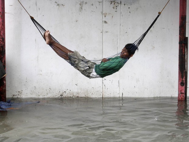 Outro morador dorme em rede do lado de fora de sua casa, em Quenzon City. Passagem do tufão Sanba causou enchentes em parte do país. (Foto: Cheryl Ravelo/Reuters)