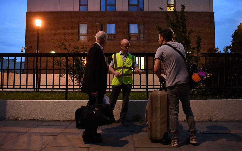 Residentes deixam o edifício Burnham Tower no norte de Londres durante desocupação para realização de obras de segurança contra incêndio, na sexta (23) (Foto: Justin Tallis/AFP)