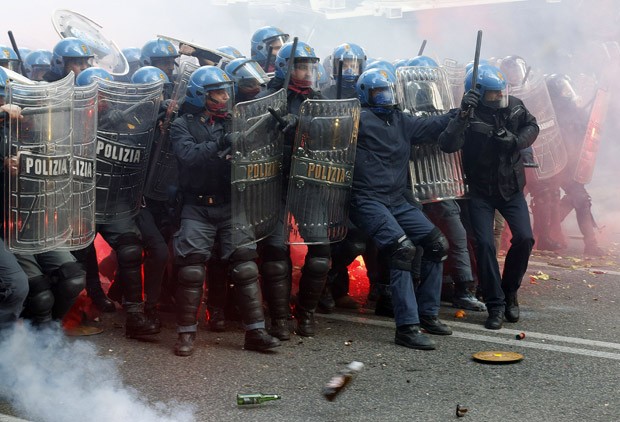 Policiais se protegem de garrafas e pedras atirados pelos manifestantes em Roma (Foto: Alessandro Bianchi/Reuters)