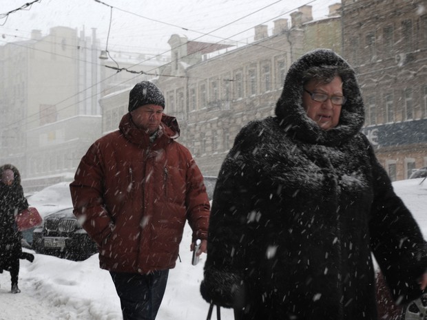 Pessoas andam através de uma forte nevasca em Moscou em foto de arquivo do dia 25 de março. Na manhã desta segunda-feira (1°),  as temperaturas chegaram a 2 ° C  na capital russa (Foto:  AFP PHOTO / Andrey Smirnov)