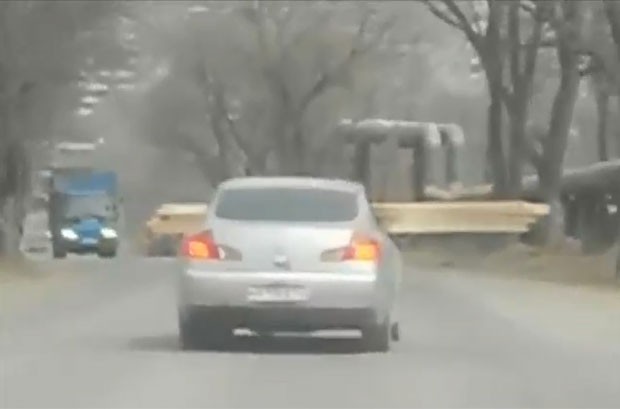 Motorista é flagrado dirigindo carro 'atravessado por madeira' na Rússia (Foto: Reprodução/Youtube)