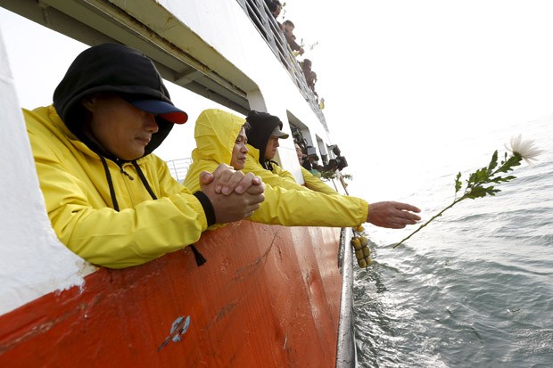 Familiares de vítimas do naufrágio da balsa Sewol jogam flores ao mar durante homenagem feita em um passeio pelas águas próximas à ilha de Jindo (Foto: Jeon Heon-Kyun/Reuters/Pool)