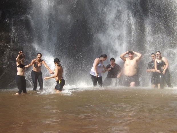 Grupo de turistas aproveita a queda da cachoeira durante dia de sol forte (Foto: Alan Schneider / G1)