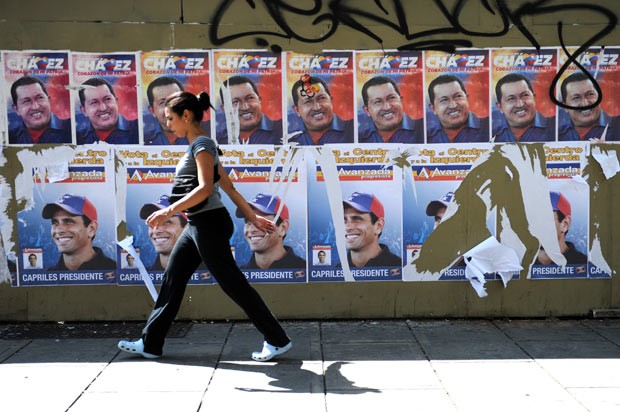 Venezuelana passa diante de cartazes de campanha de Chávez e Capriles, em Caracas (Foto: Rodrigo Arangua / AFP)