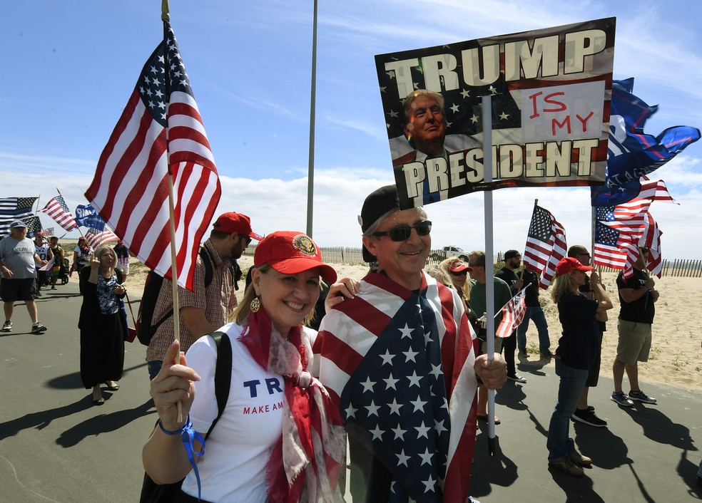 Manifestantes marcham em apoio a Donald Trump neste sábado (25) em Huntington Beach, na Califórnia (Foto: Mark RALSTON / AFP)