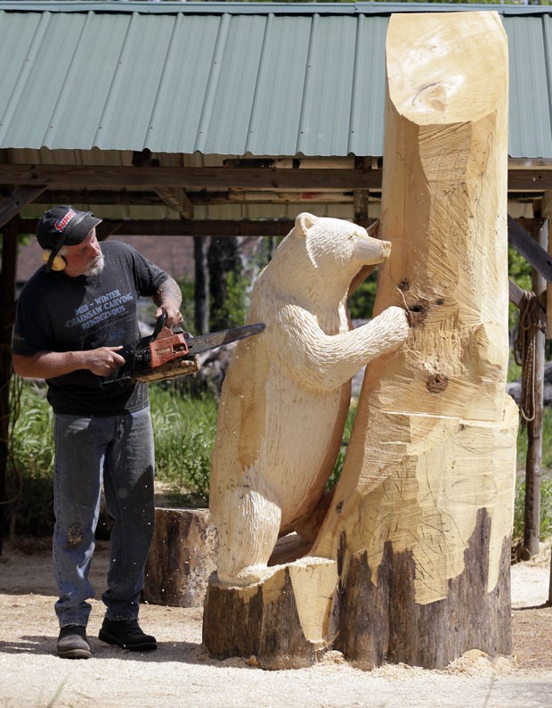 Mark Tyoe trabalha em escultura de madeira feita com motosserra em Nova York, nos EUA (Foto: Mike Groll/AP)