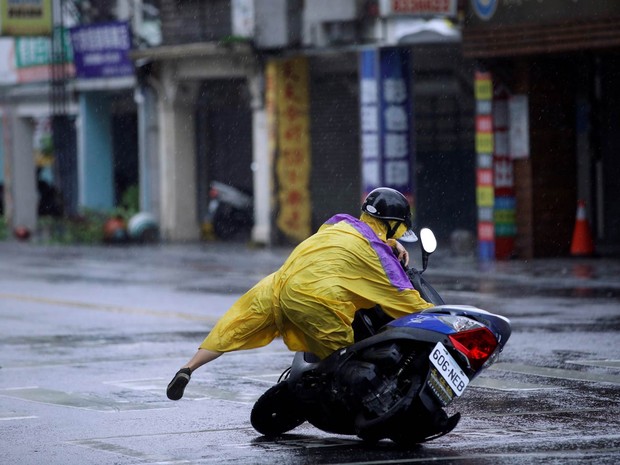 Motociclista escorrega e toma um tombo com sua moto no asfalto molhado enquanto o tufão Megi passa por Hualien, no leste de Taiwan (Foto: Tyrone Siu/Reuters)