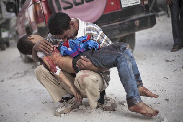 Homem chora abraçado ao corpo do filho morto em atentado na cidade síria de Aleppo (Foto: Manu Brabo/AP)