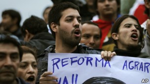 Manifestante pró-Lugo carrega cartaz em defesa da reforma agrária em protesto em Assunção (Foto: AP)