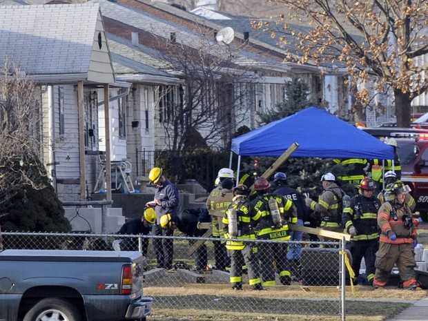 Policiais e bombeiros examinam uma das casas atingidas pela queda de um jato particular neste domingo (17) nos Estados Unidos  (Foto: AP Photo / Joe Raymond)
