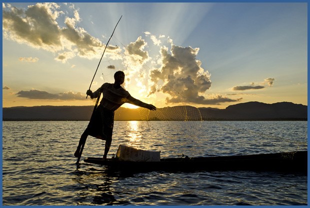 No pôr-do-sol, um pescador da etnia Intha joga sua rede no lago Inle. Equilibrado em um só pé, ele rema com a outra perna (Foto: Haroldo Castro/ÉPOCA)