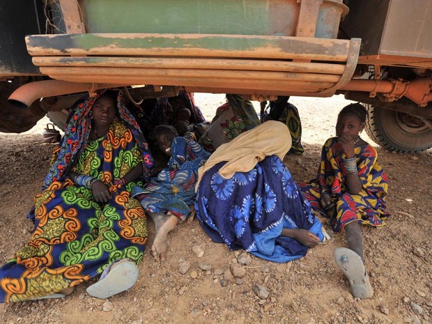 Refugiados do Mali sentam debaixo de um caminhão no campo de refugiados 200 km a noroeste de Niamey, no Níger. (Foto: Issouf Sanogo/AFP)