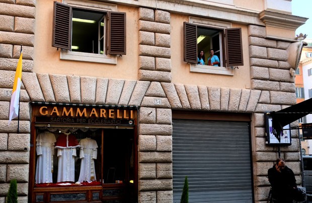 Costureiras aparecem na janela para ver a movimentação em frente a loja (Foto: Alberto Pizzoli/AFP)