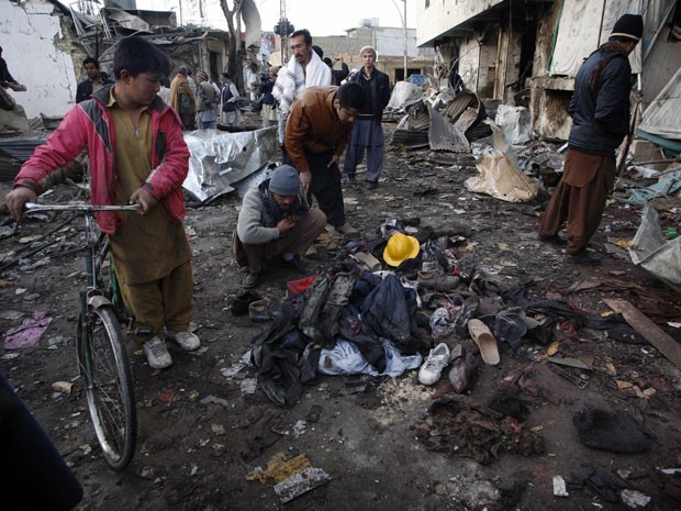 Familiares procuram pertences de vítimas em meio aos escombros na cidade de Quetta (Foto: Naseer Ahmed/Reuters)