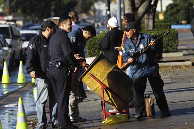 Policiais verificam armas entregadas por americanos em troca de vales-presente nesta quarta-feira (25) na cidade americana de Los Angeles (Foto: Reuters)