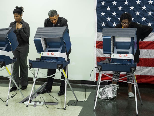 Ao lado de duas eleitoras, Barack Obama vota antecipadamente no Dr. Martin Luther King Community Service Center, em Chicago, Illinois, na segunda-feira (20) (Foto: AFP Photo/Brendan Smialowski)